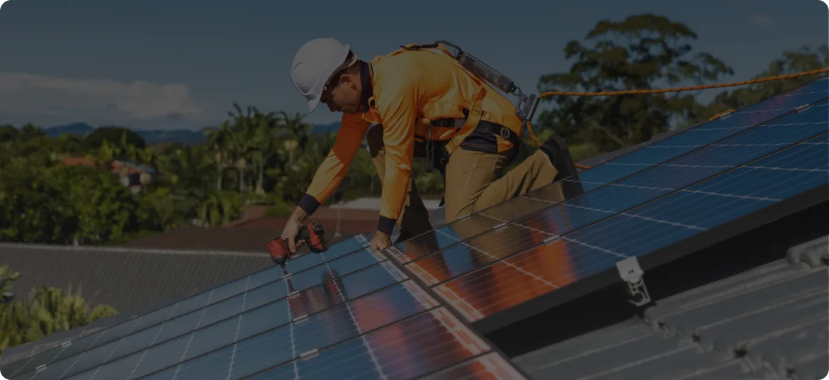 A solar installer fitting panels on the roof of an Australian home